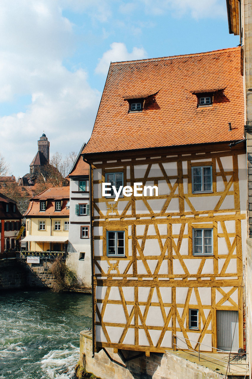 Houses by river in town against sky