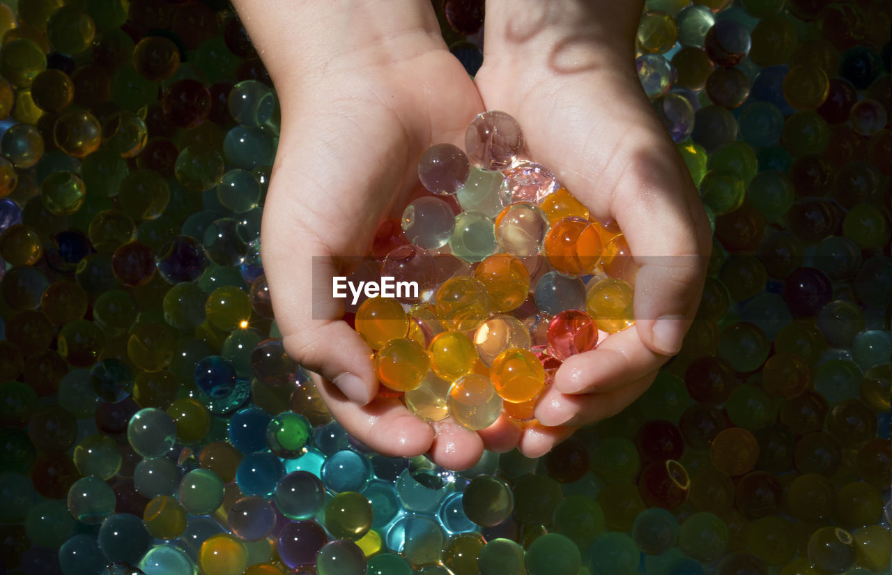 hand, yellow, one person, holding, multi colored, bead, close-up, abundance, large group of objects, nature, food and drink, green, art, food, flower, childhood, directly above, hands cupped, indoors, adult