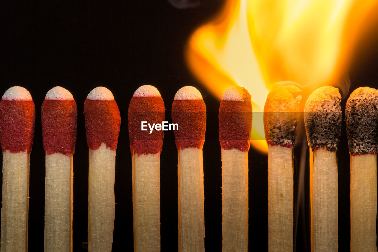 Close-up of burning matchsticks against black background