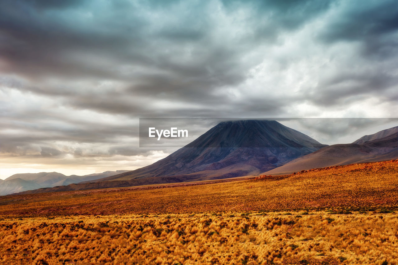 Scenic view of mountain range against cloudy sky