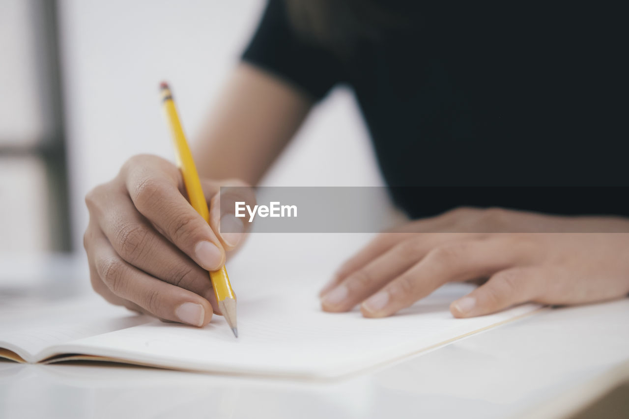 Close up hands with pen writing on notebook.