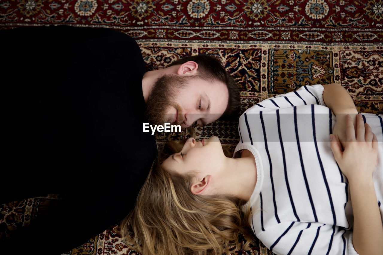 High angle view of smiling romantic couple lying on carpet at home