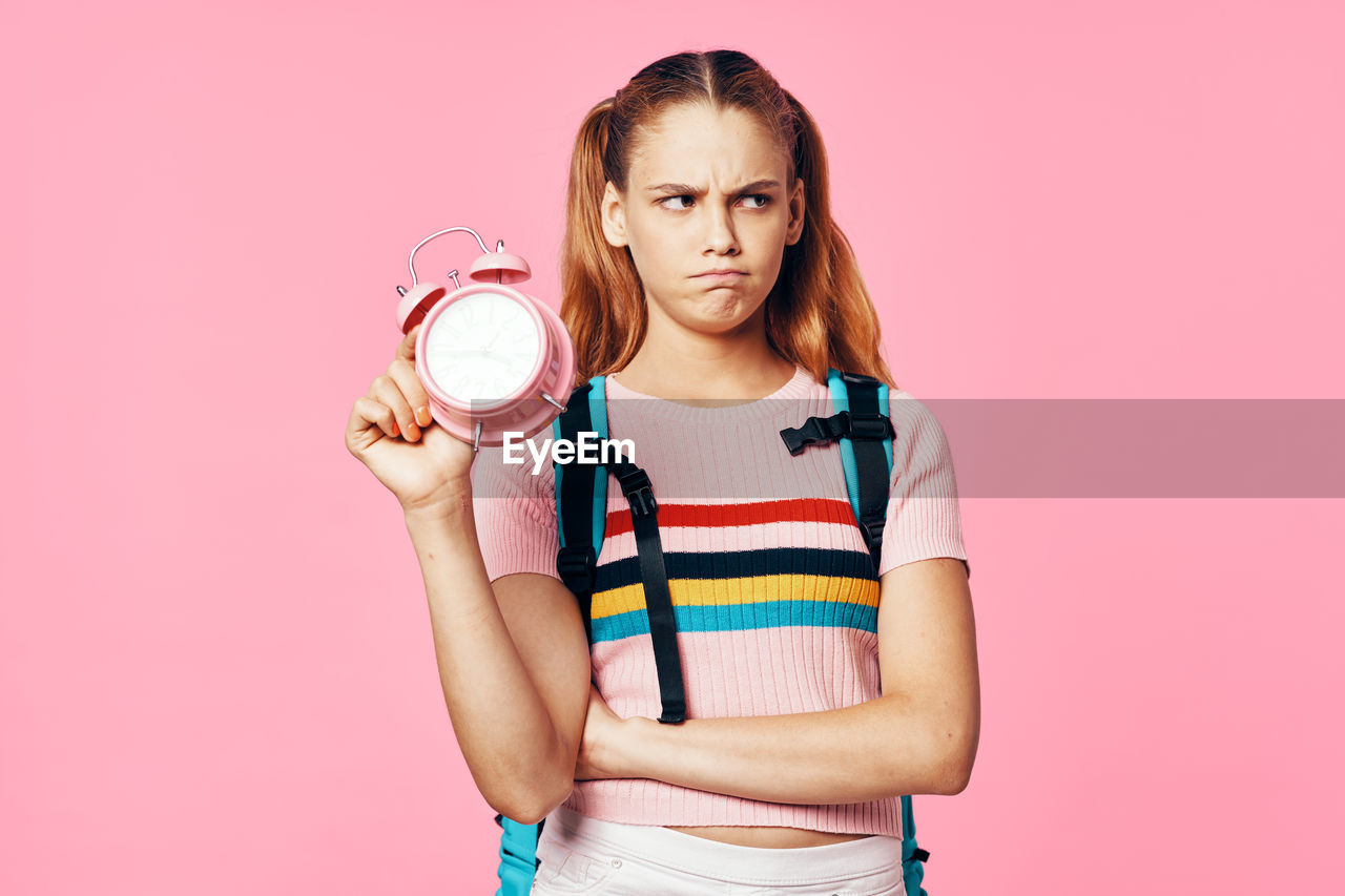 PORTRAIT OF WOMAN WITH PINK HAIR AGAINST COLORED BACKGROUND