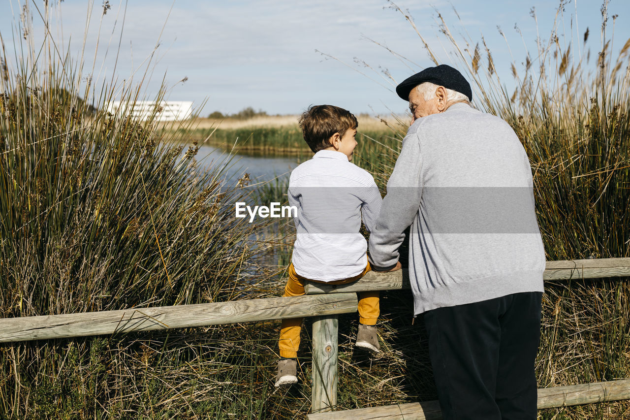 Back view of little boy and his grandfather looking at each other