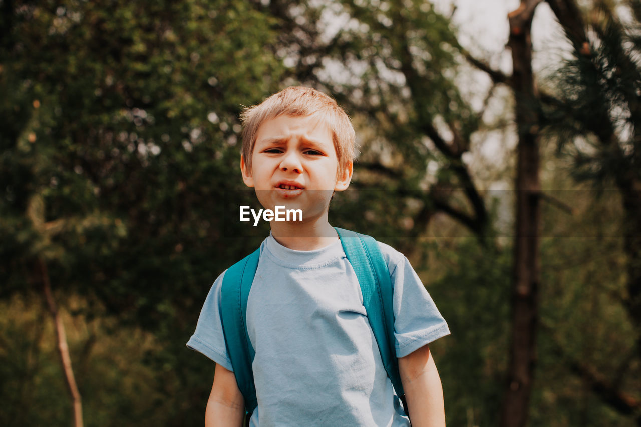 Portrait of boy standing against trees
