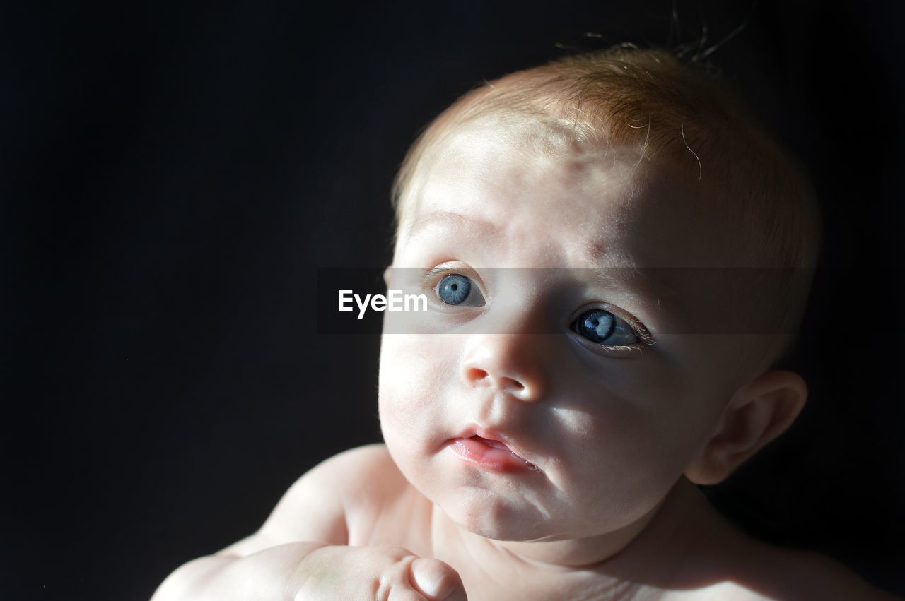 Close-up of cute baby boy looking away in darkroom