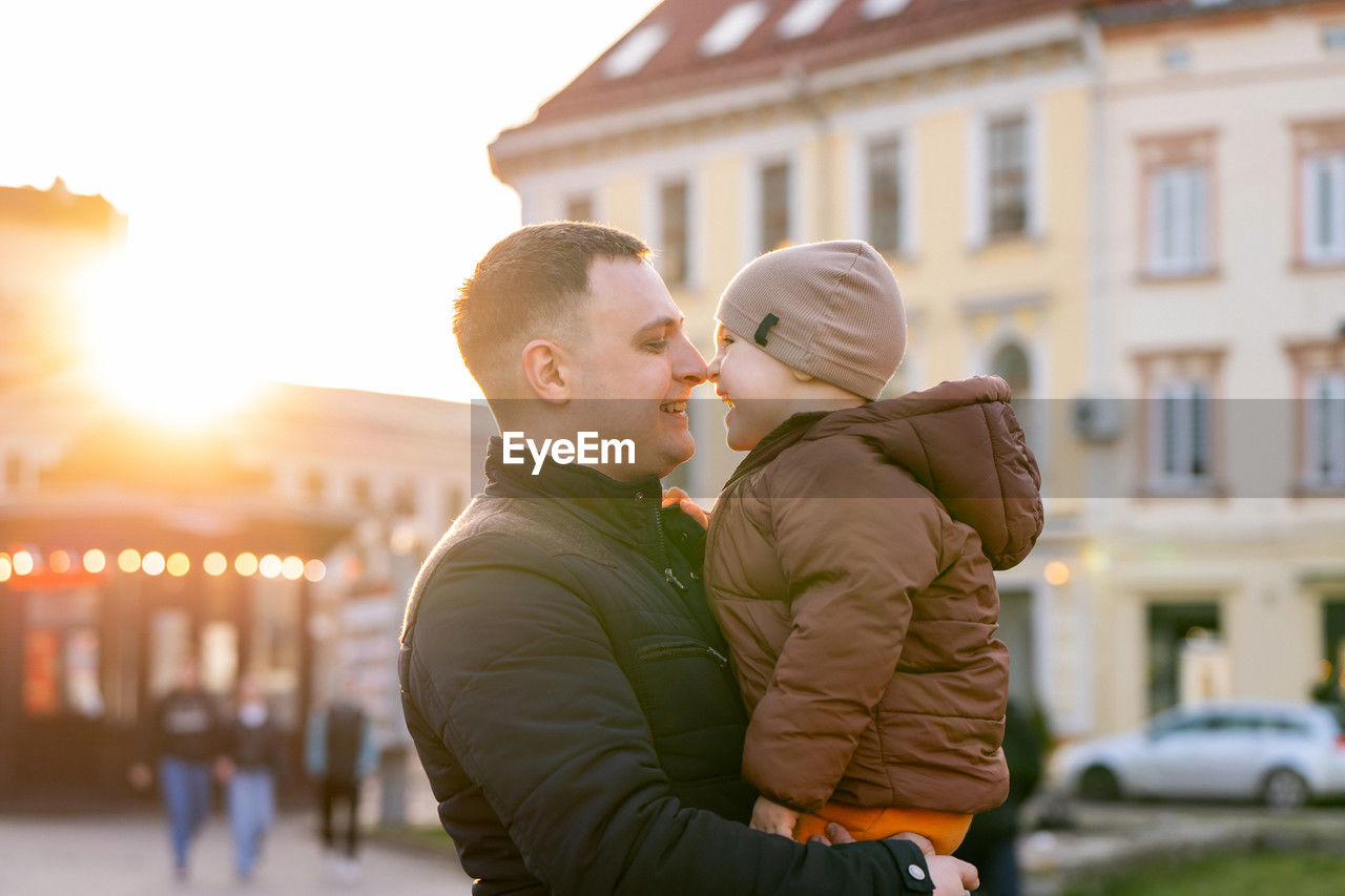 A happy father and three year old son hug in a city street. warm relationships between parents 