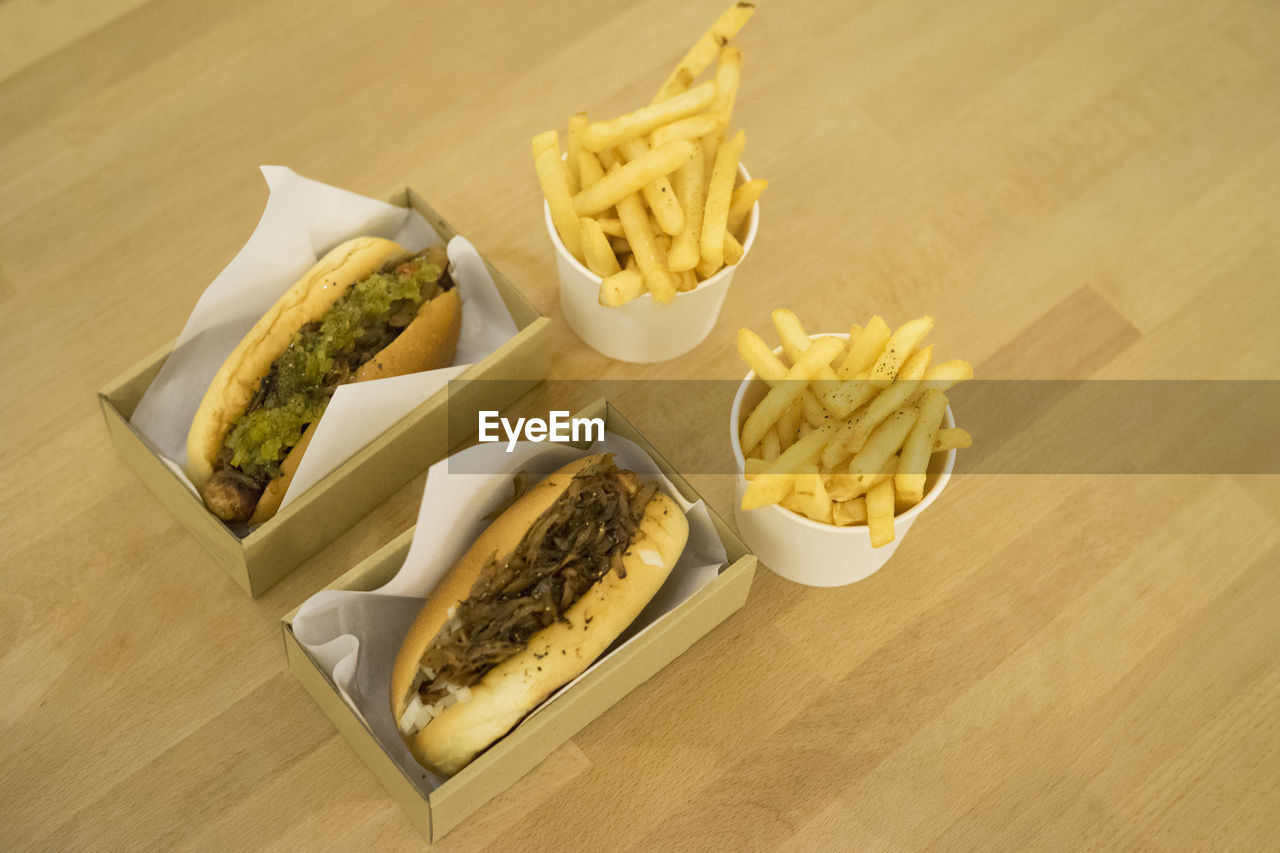 High angle view of french fries and hot dog on wooden table