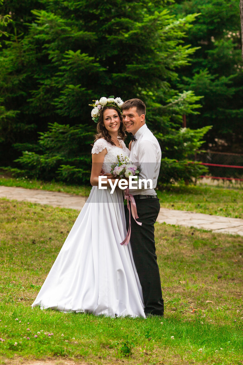 portrait of smiling couple standing on grassy field