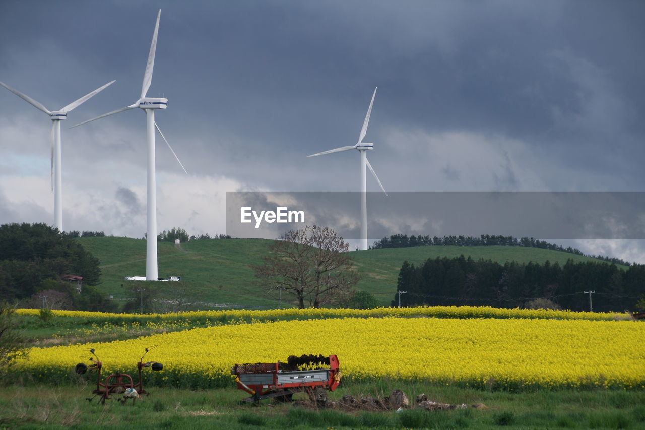 Windmills on field against sky