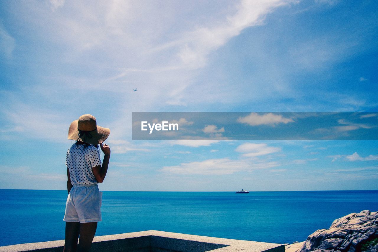 Rear view of woman wearing hat looking at sea against sky