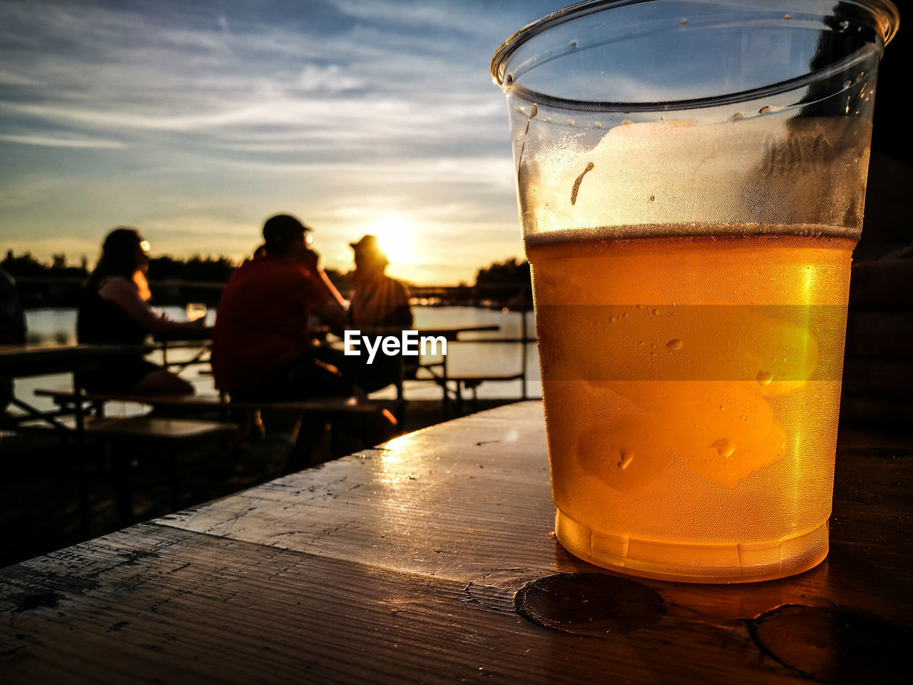 Beer glass on table against sky during sunset