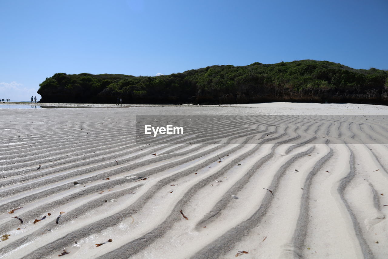 land, sand, sky, beach, landscape, nature, environment, scenics - nature, water, sea, natural environment, tranquility, beauty in nature, clear sky, no people, tranquil scene, travel destinations, shore, travel, day, blue, pattern, sunny, sand dune, outdoors, non-urban scene, tourism, plant, tree, dune, holiday, vacation, coastline, trip
