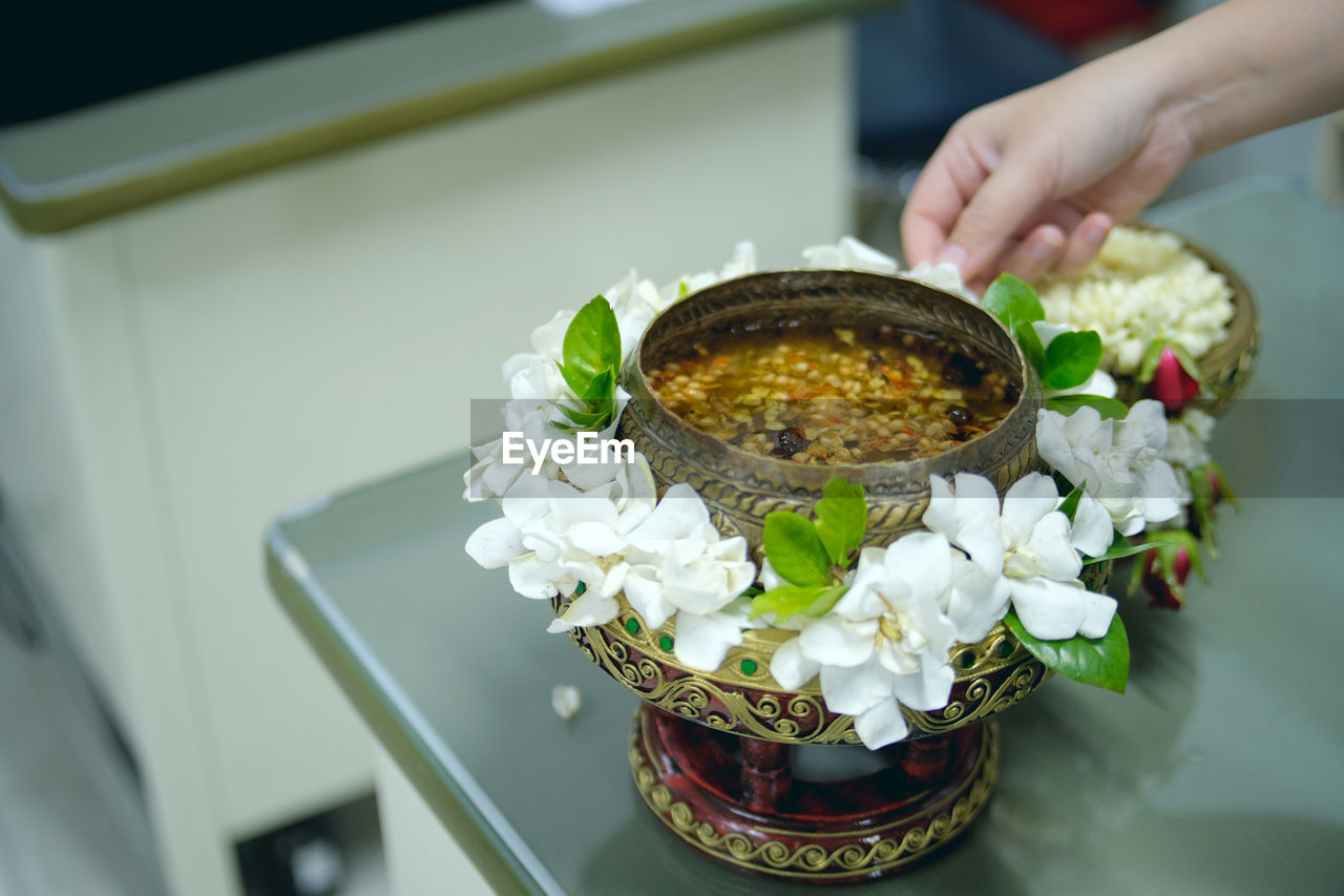 Cropped hands by food in bowls with white flowers