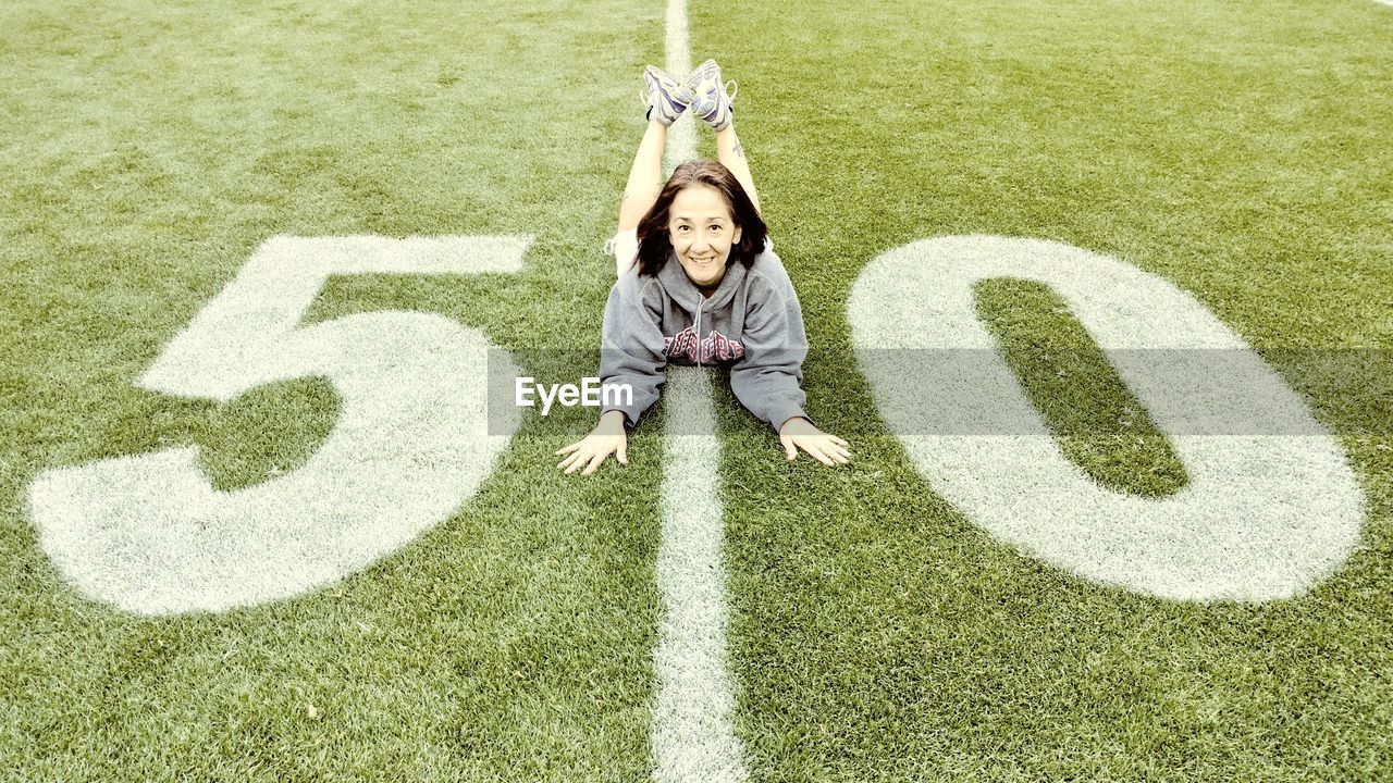 High angle portrait of woman lying on american football field