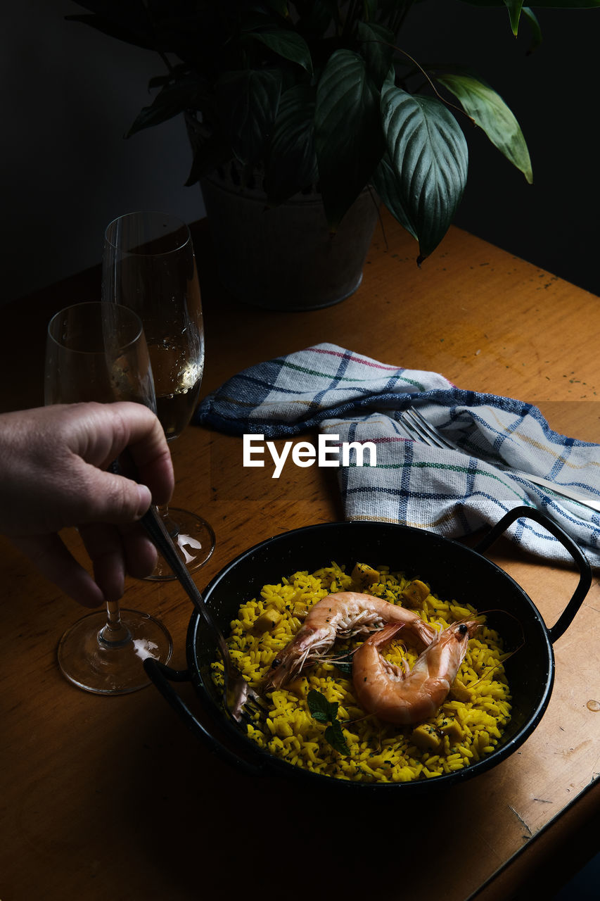 A plate of spanish paella prepared for two accompanied by two glasses