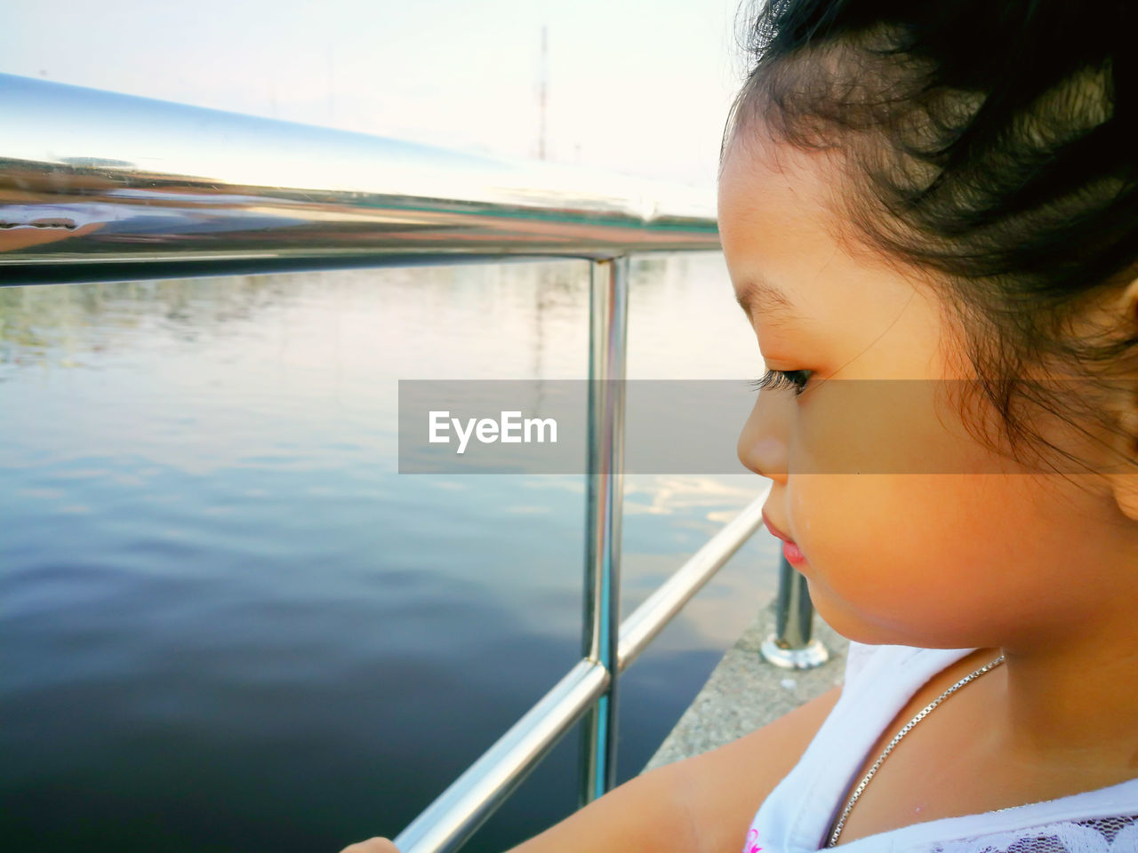 Close-up of girl standing by railing looking at lake