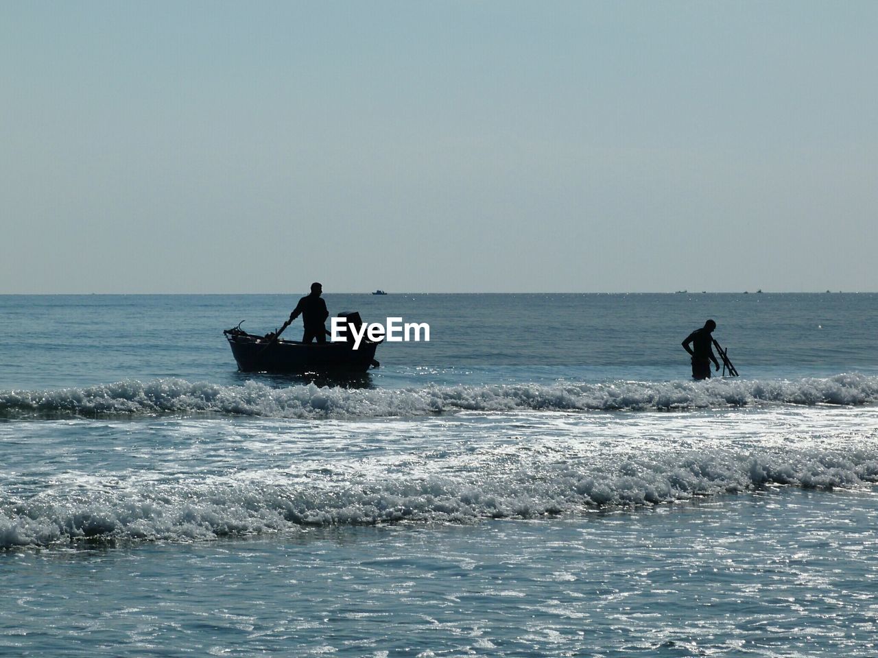 Silhouette people in sea against clear sky