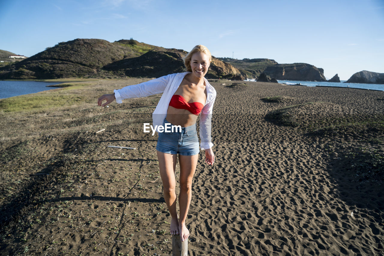 Teenage girl balancing on stick on the beach