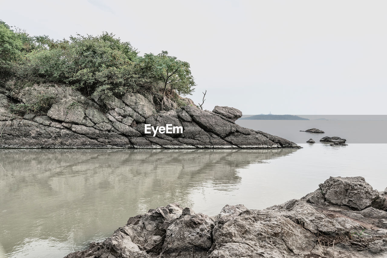 Rock formations by sea against clear sky