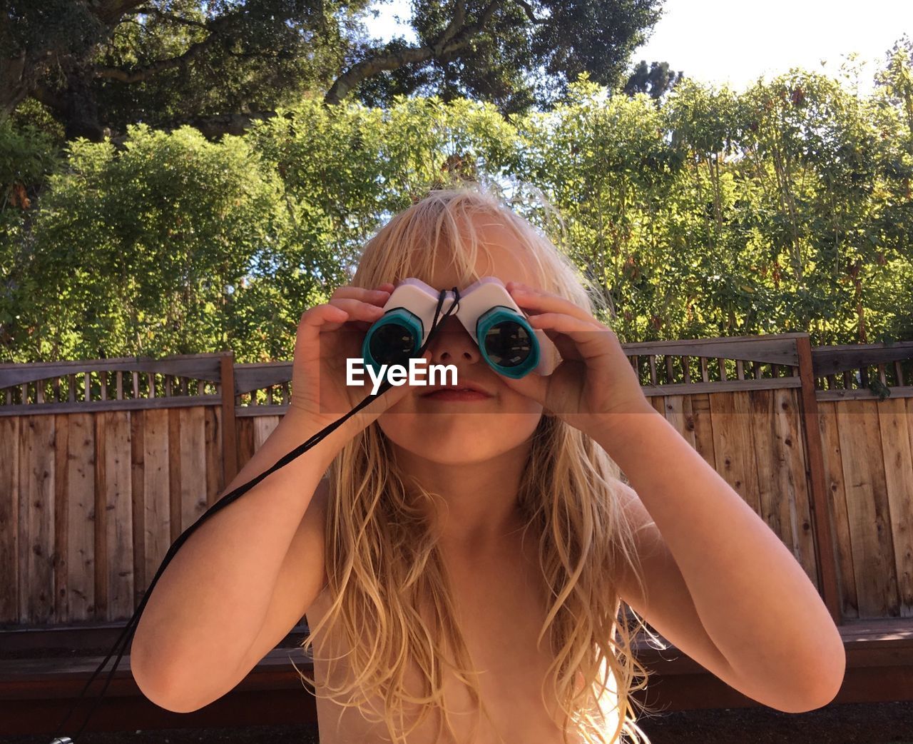 Close-up of topless girl using binoculars