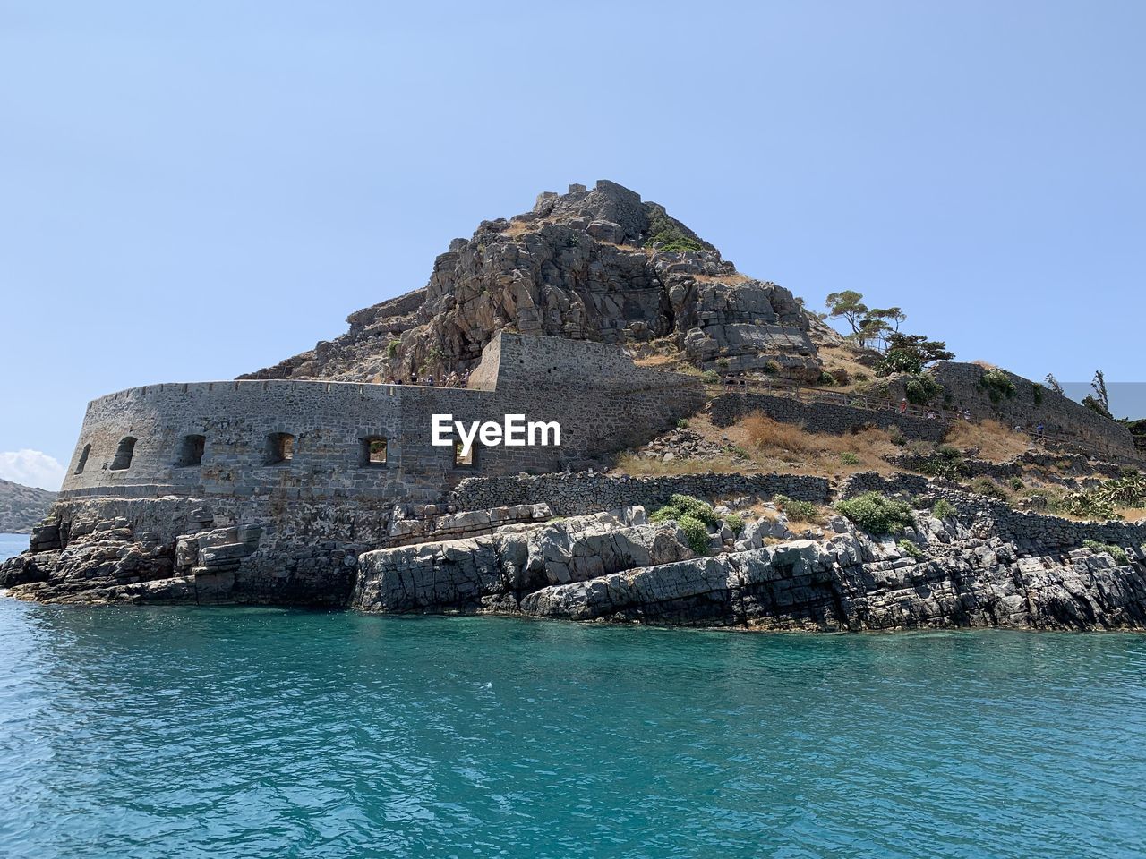 Scenic view of rock formation in sea against clear blue sky