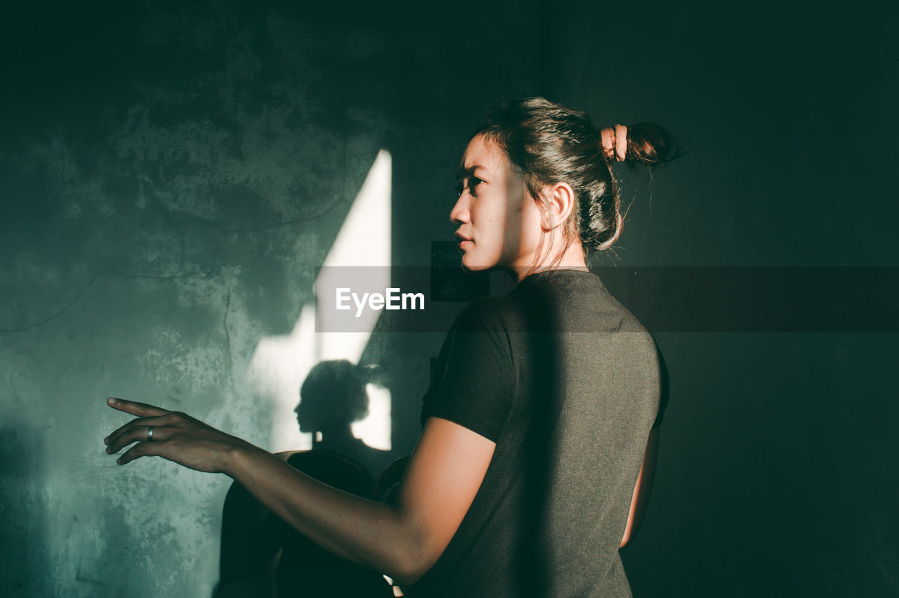 Rear view of young woman against wall