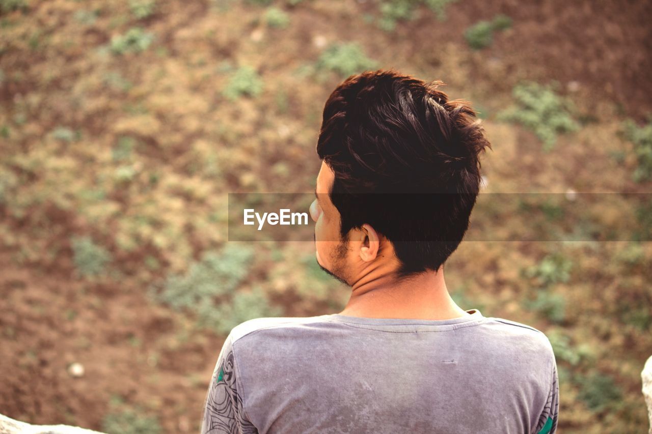 Rear view of young man looking away on land