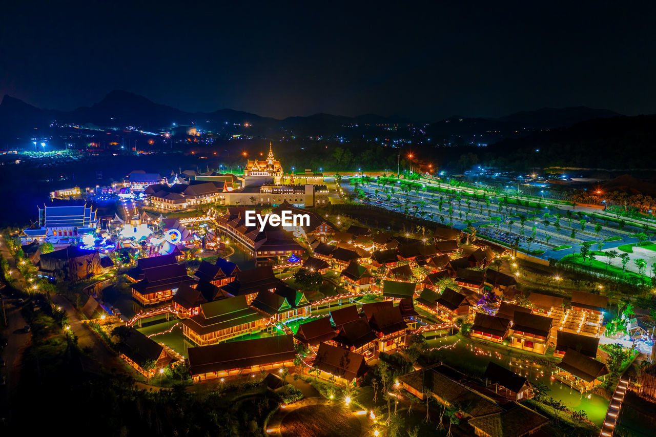 HIGH ANGLE VIEW OF ILLUMINATED BUILDINGS IN CITY AGAINST SKY