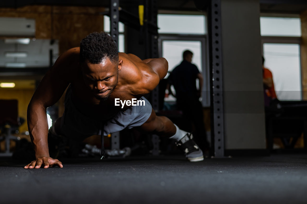 African american man doing one arm push ups in the gym. 