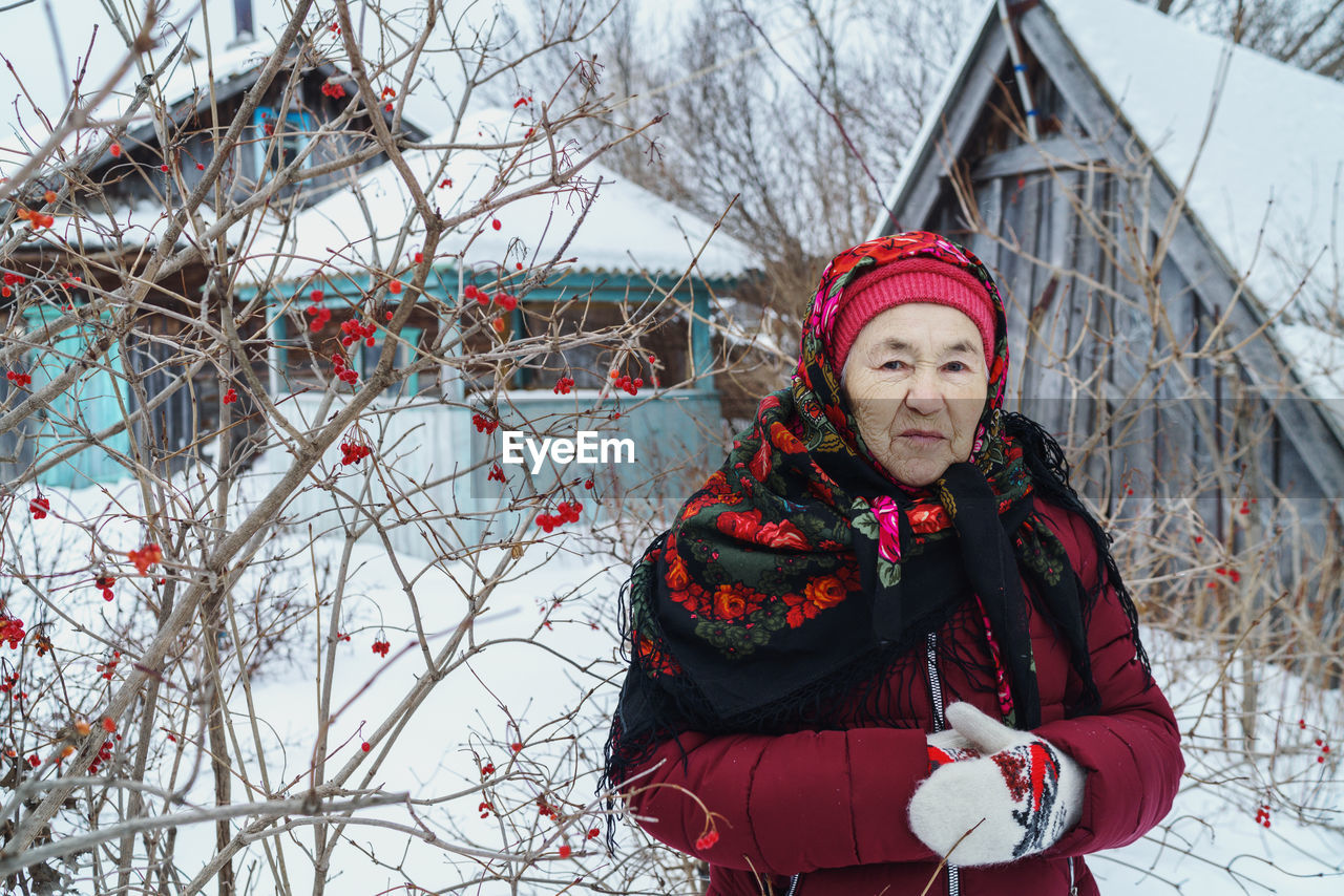 Portrait of woman with red shawl against trees with red berries during winter