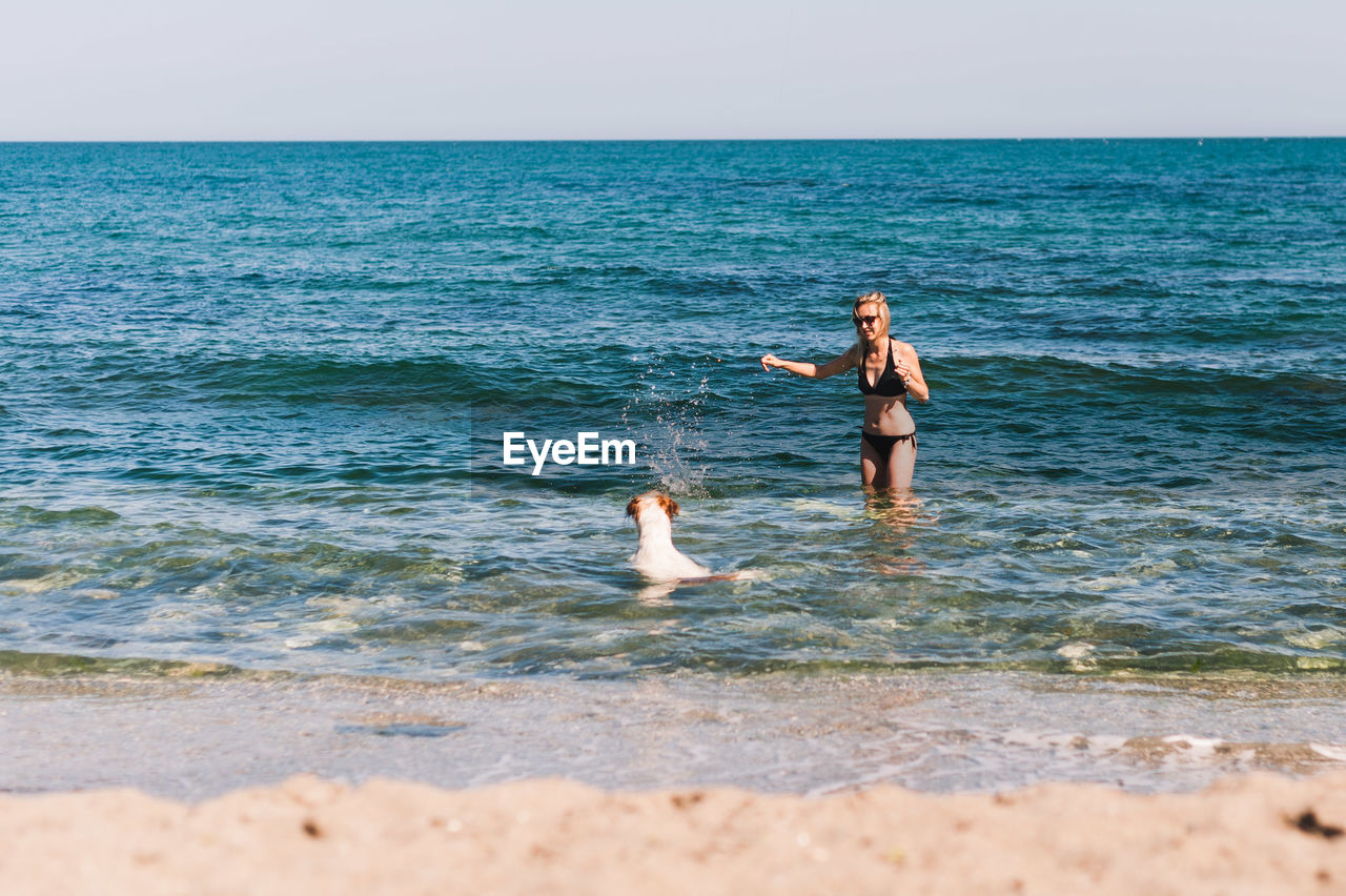 Woman in bikini with dog in sea