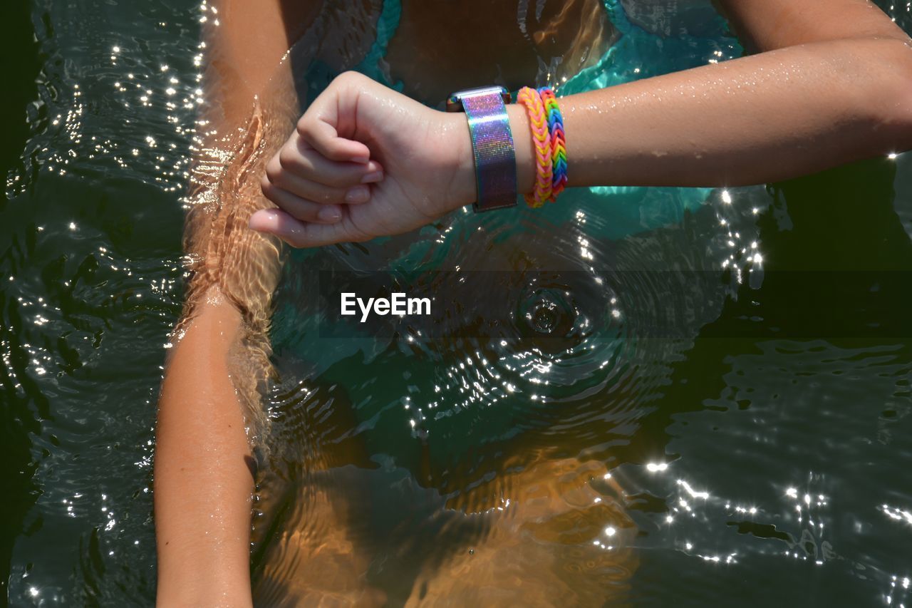 Midsection of woman checking the time while swimming in river