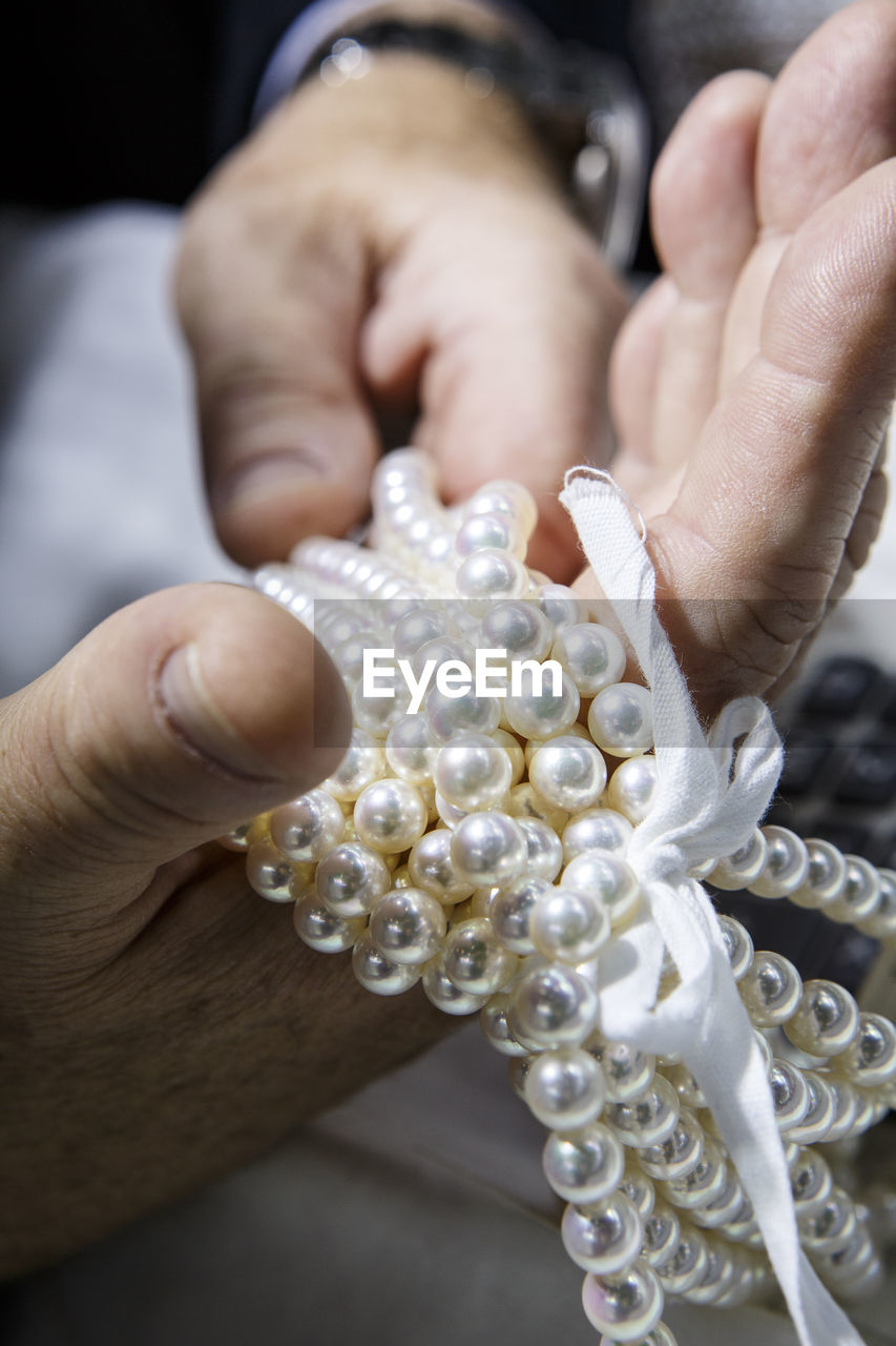 Cropped hands holding pearl jewelry