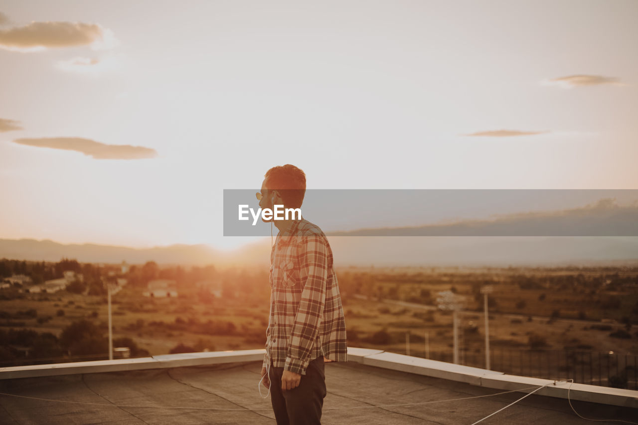 Man standing on terrace against sky during sunset