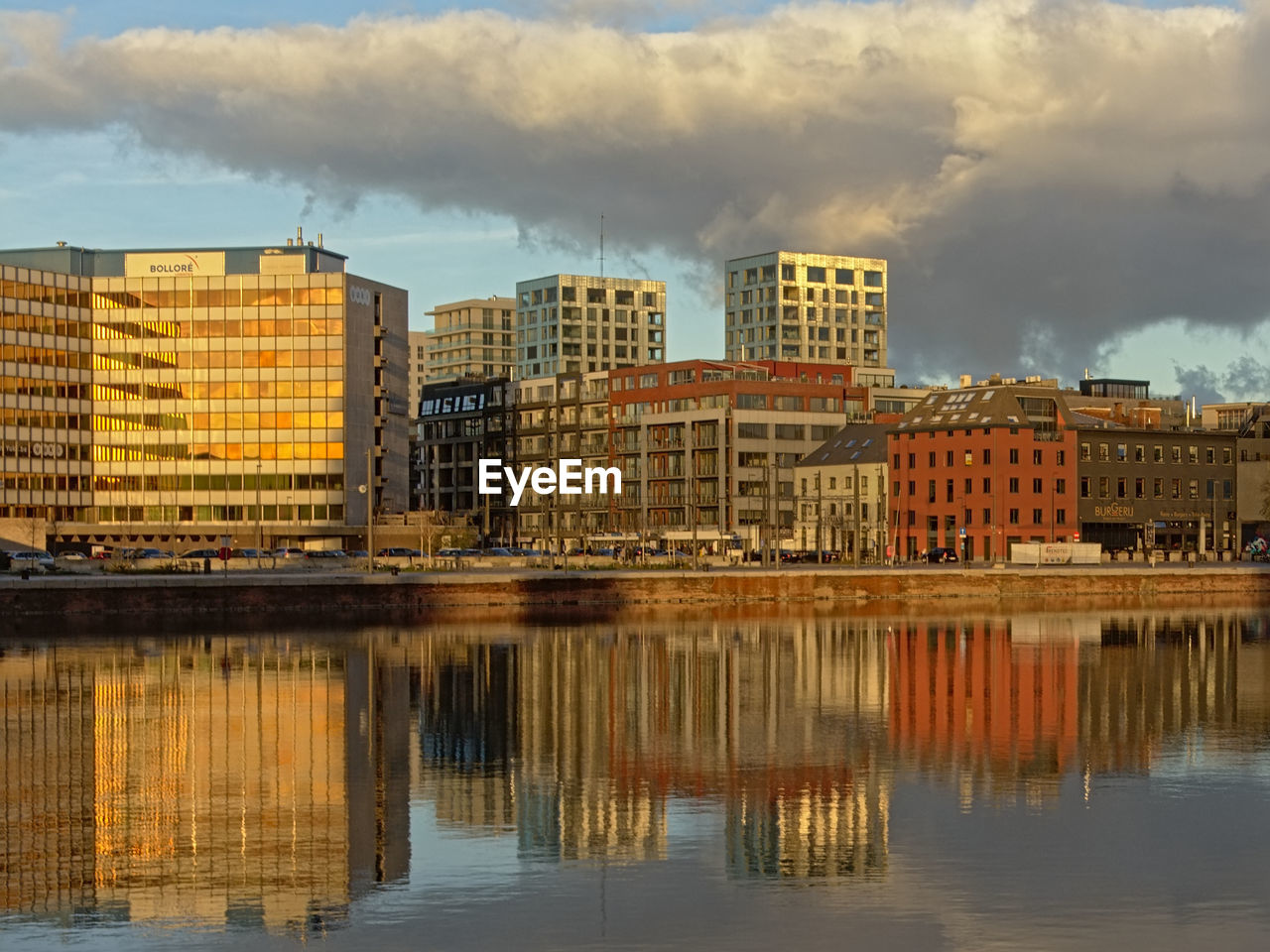 REFLECTION OF BUILDINGS IN RIVER AGAINST SKY IN CITY