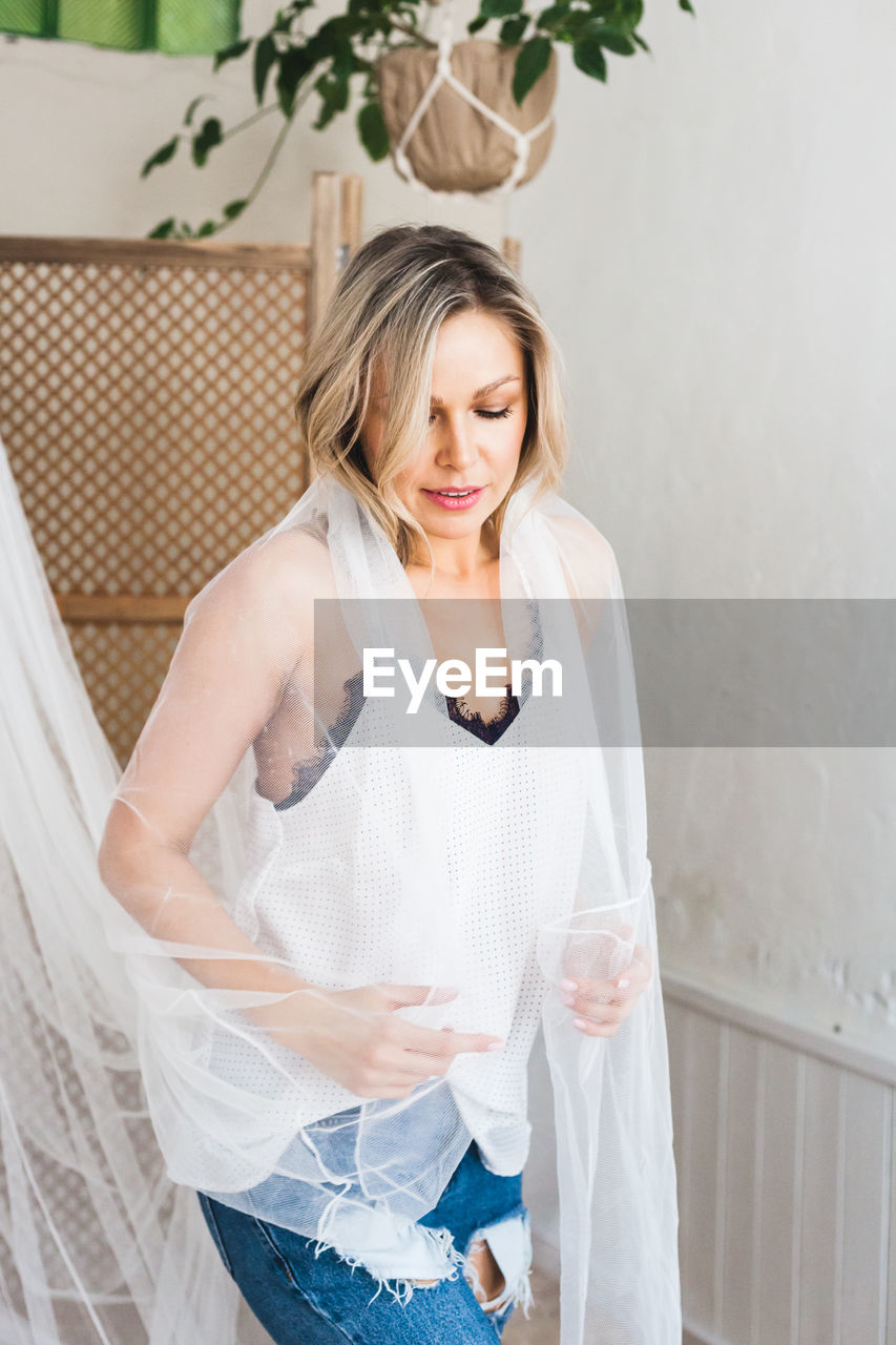 Beautiful woman holding textile standing at home