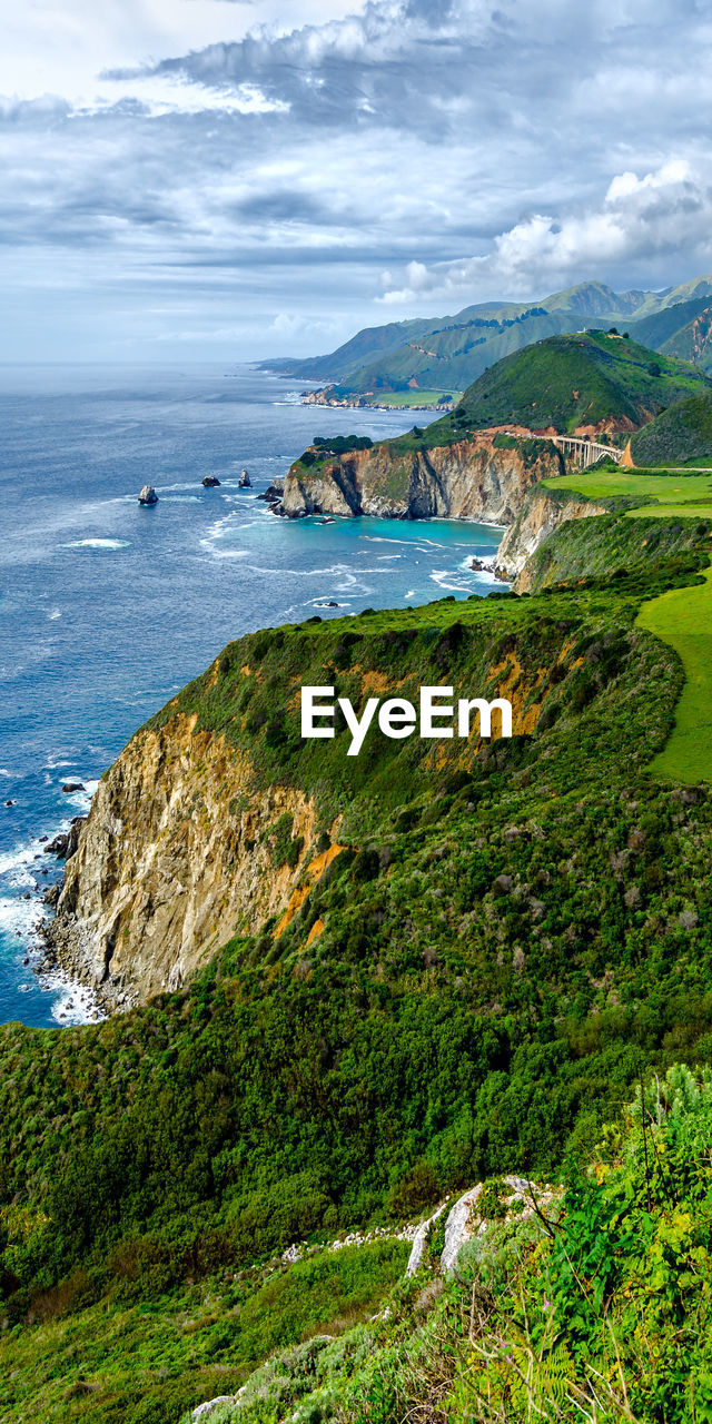 Scenic view of sea by mountains against sky