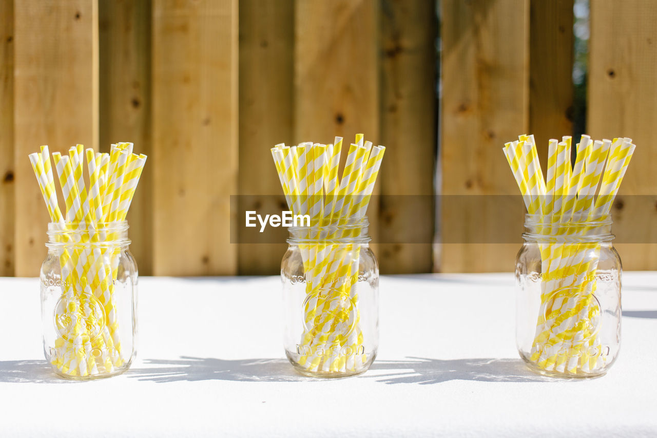 Close-up of drinking straws in jars on table