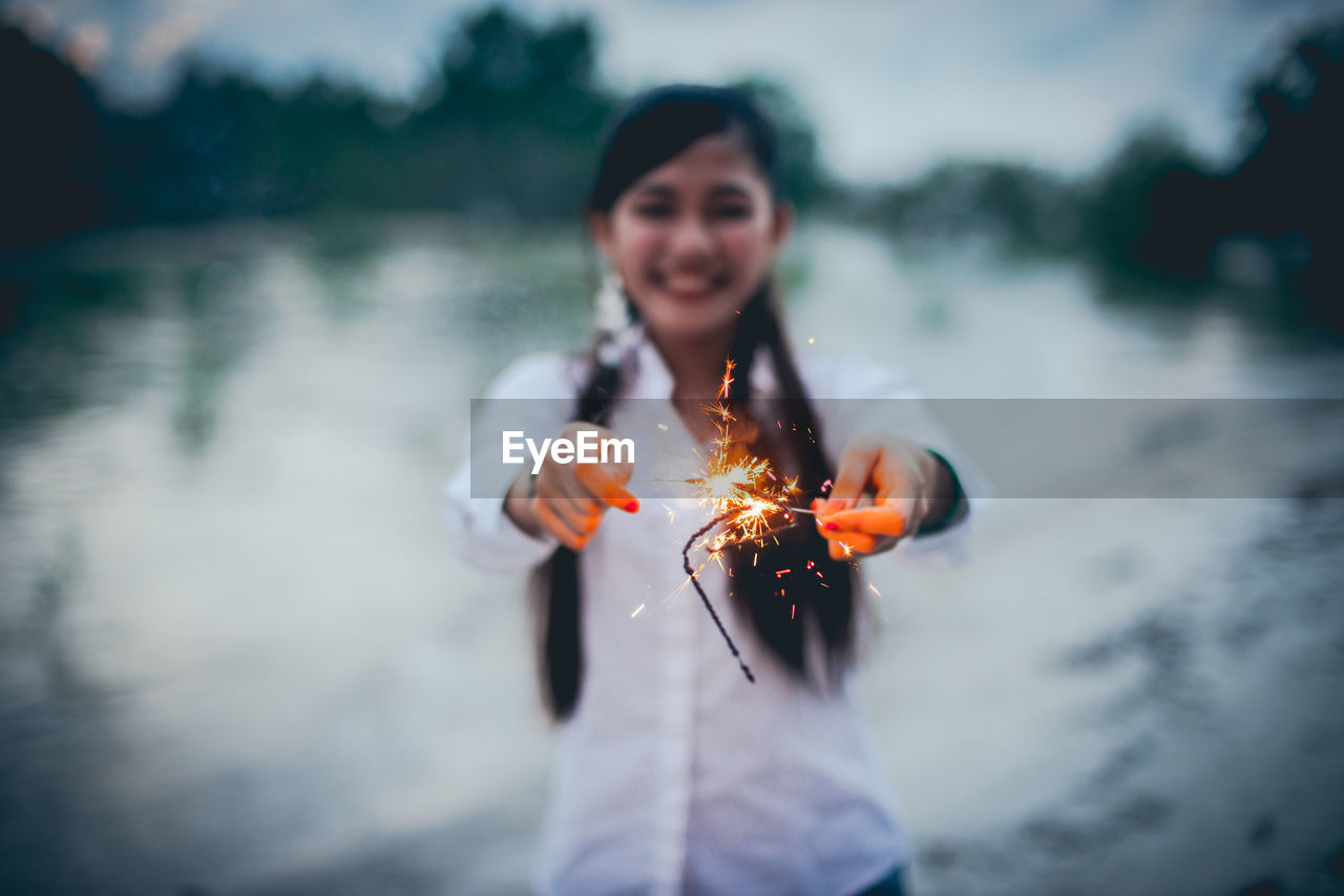 SMILING YOUNG WOMAN STANDING ON FIRE