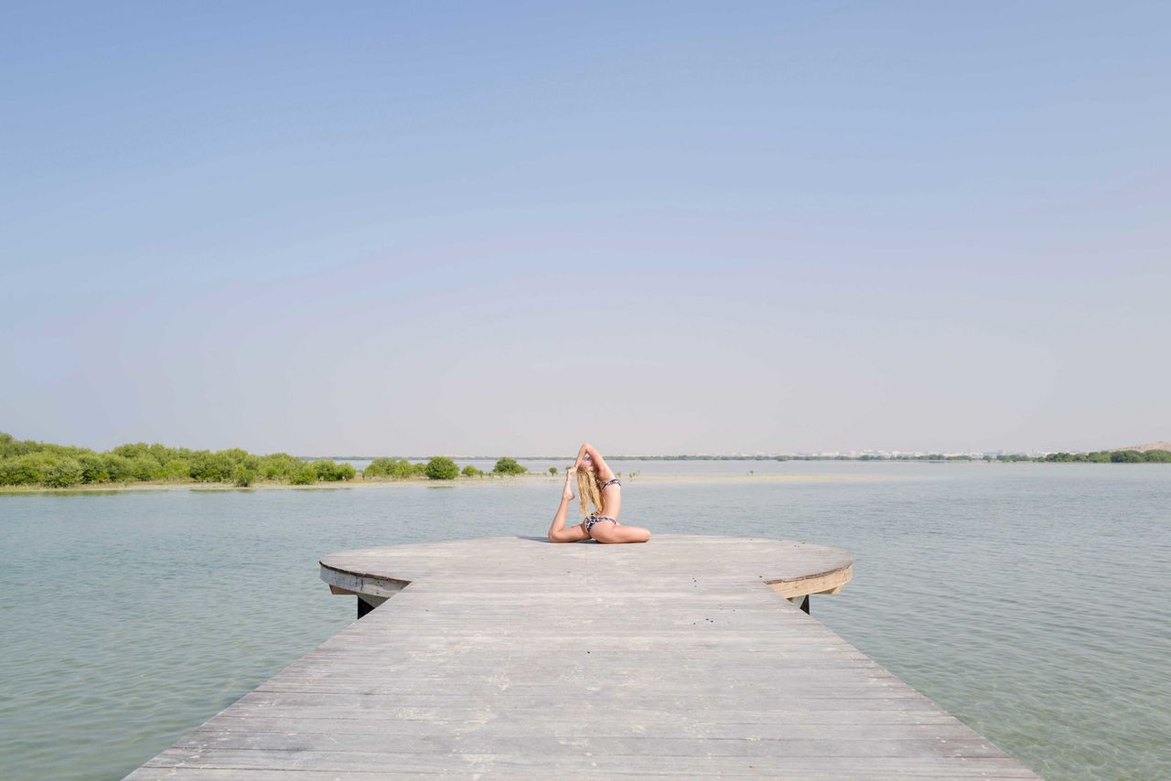 Rear view of woman standing by sea against clear sky