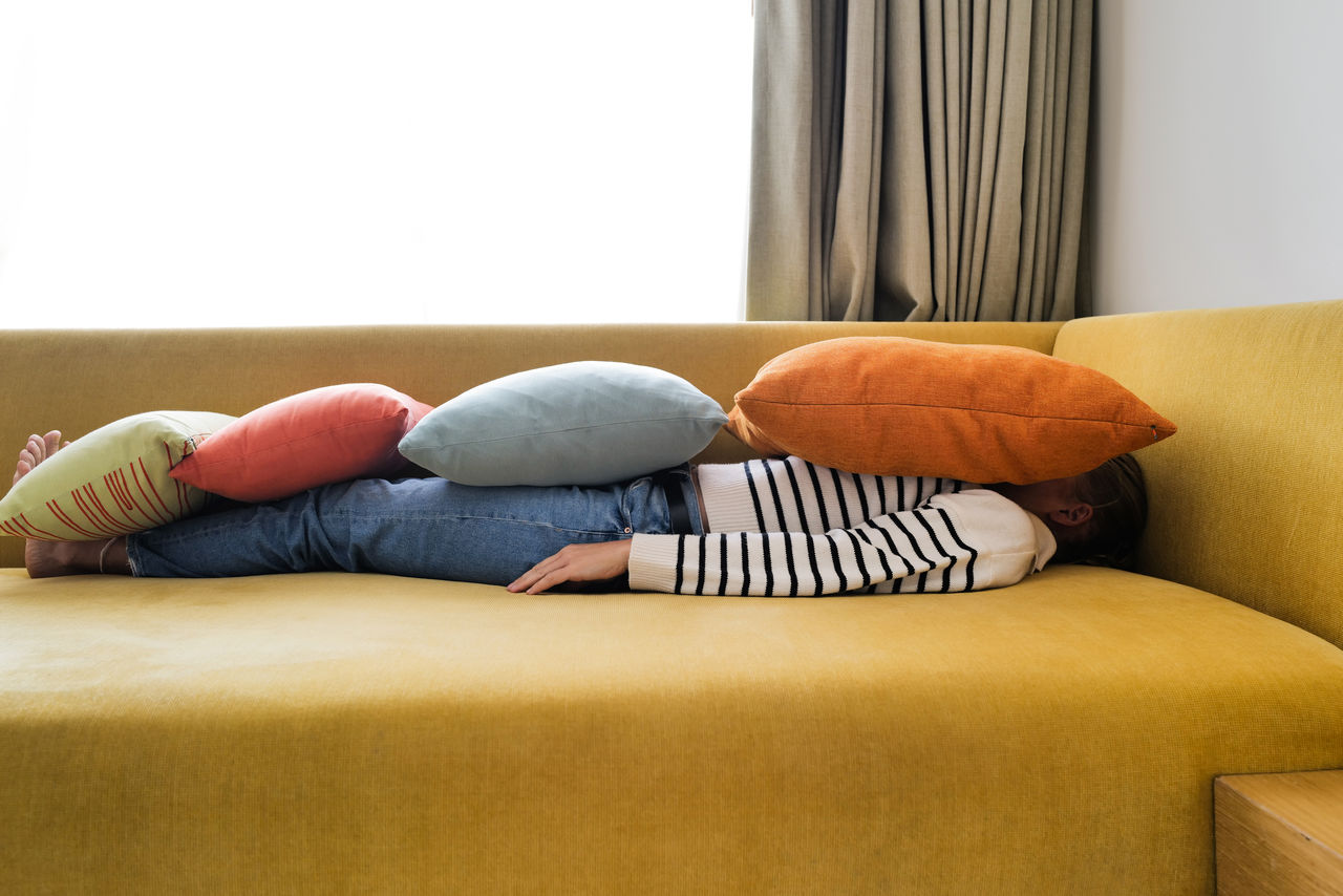 Woman relaxing on the sofa with colorful pillows on top of her body