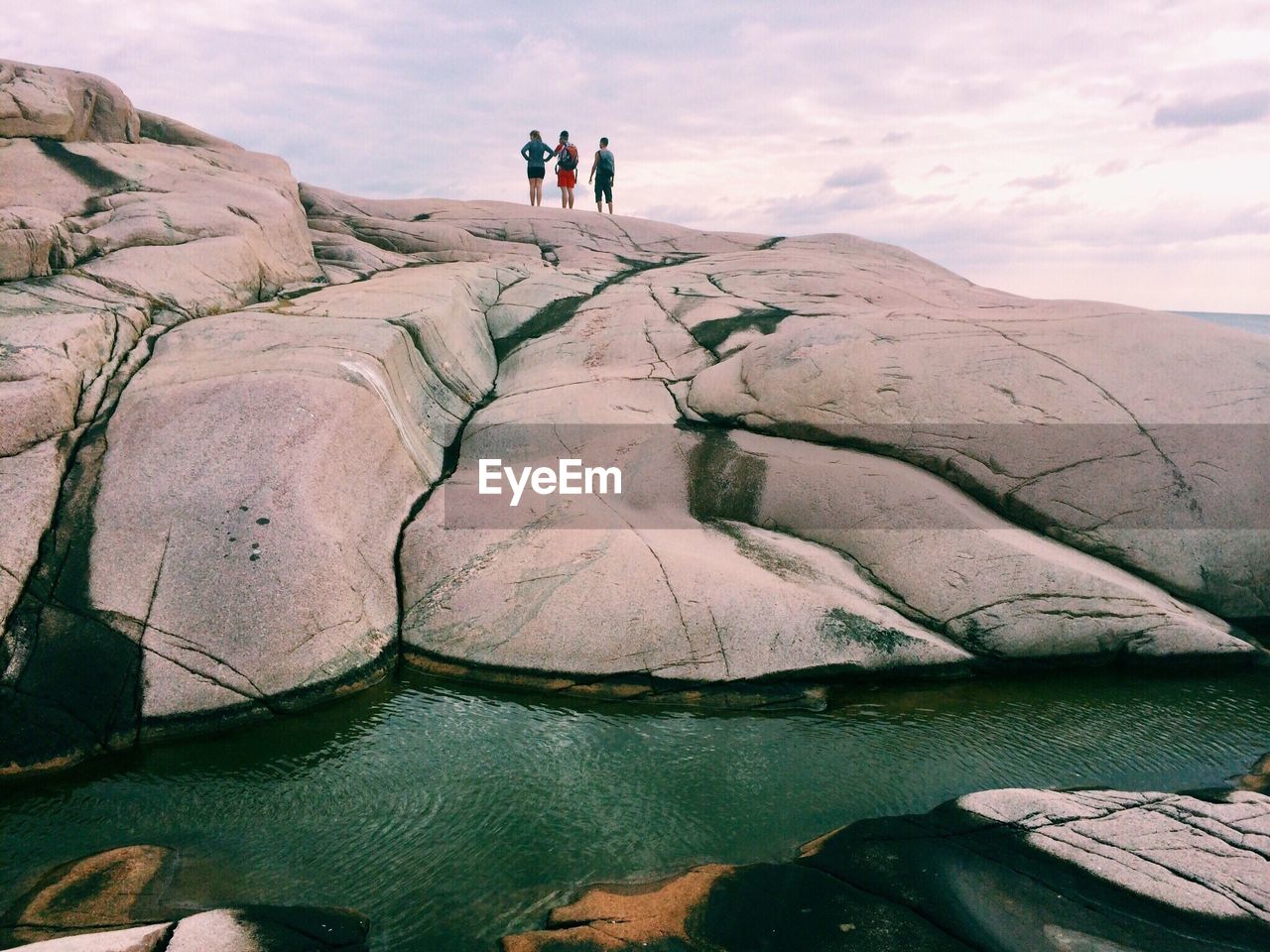 People on rock formation against sky