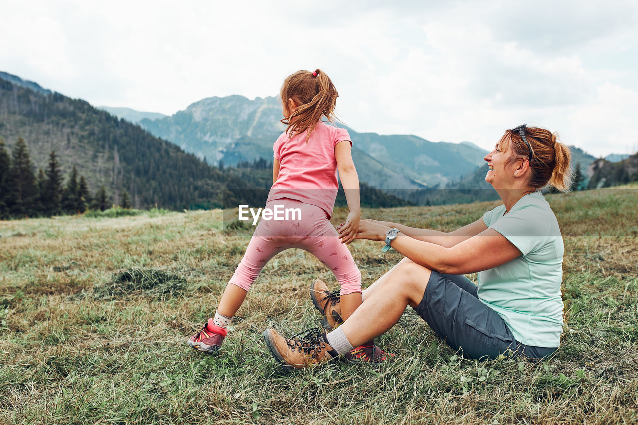 Little girl playing with her mother on grass enjoying summer day. happy family playing in the field