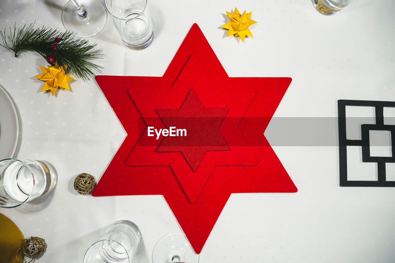 Red christmas star on white dinner table. overhead shot.