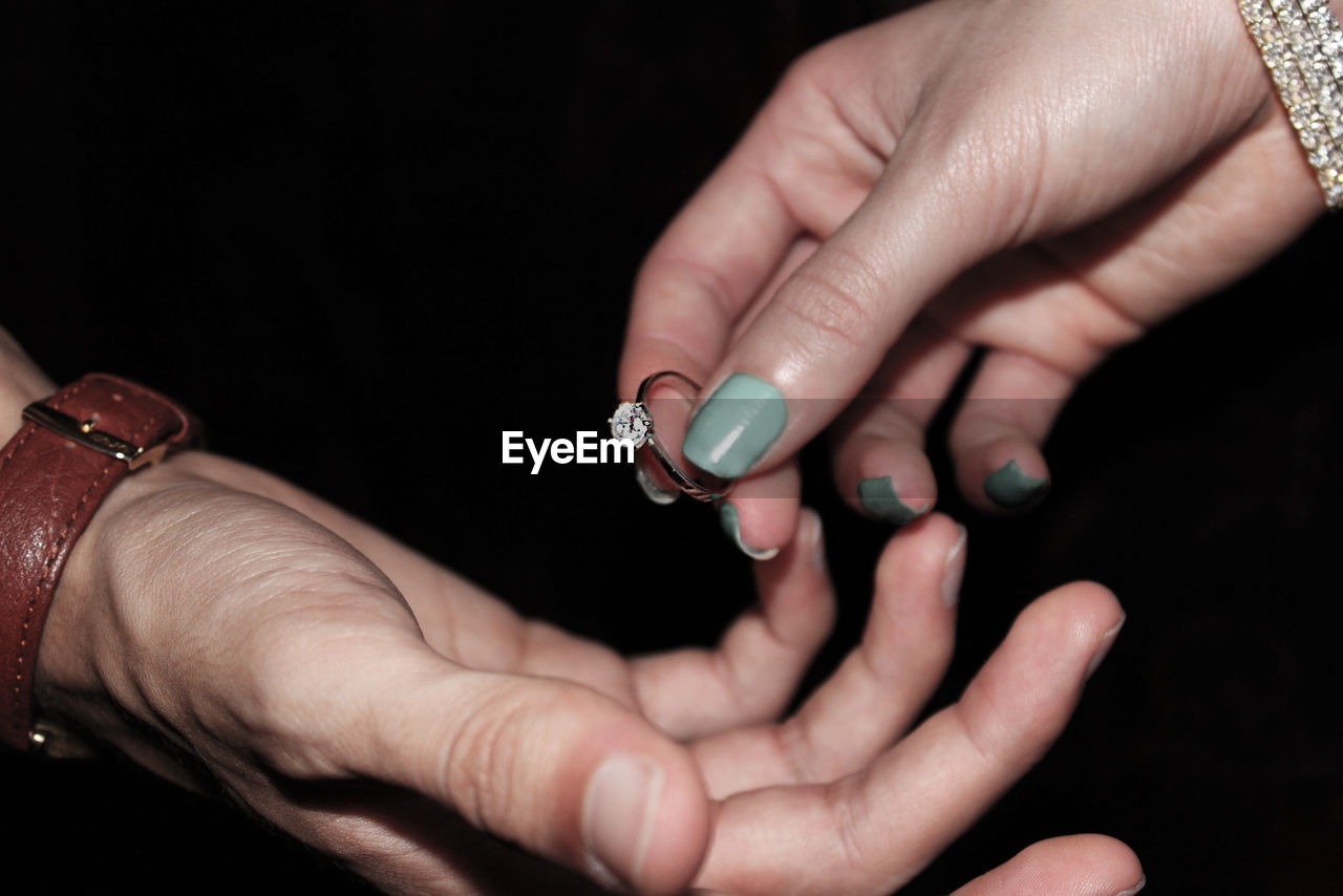 Cropped hand of woman giving ring to man