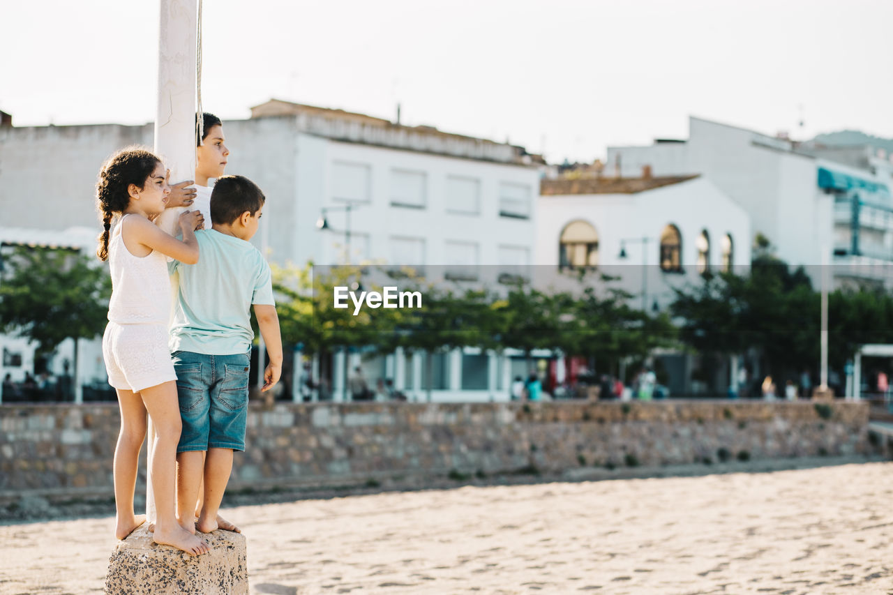 Kids standing by pole against the sky