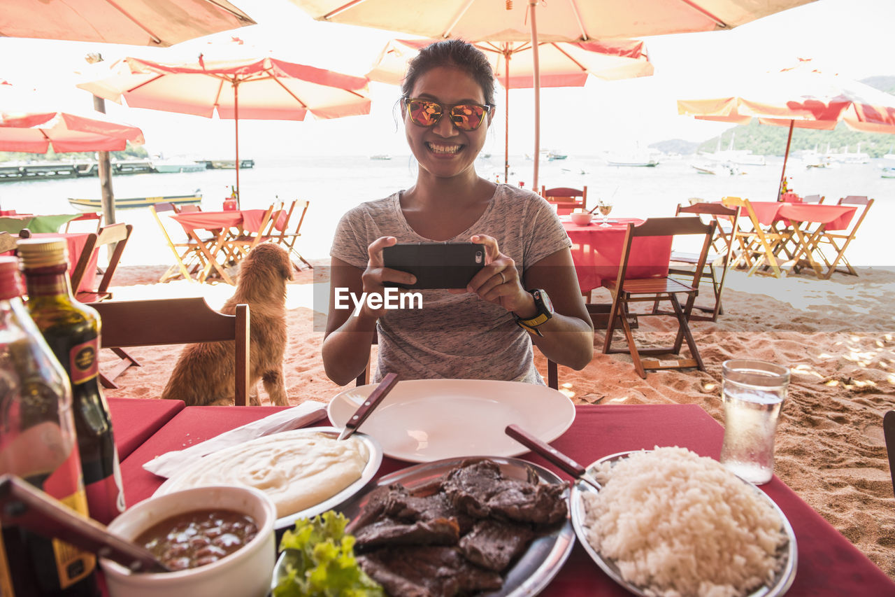 Woman at beach restaurant taking picture of food