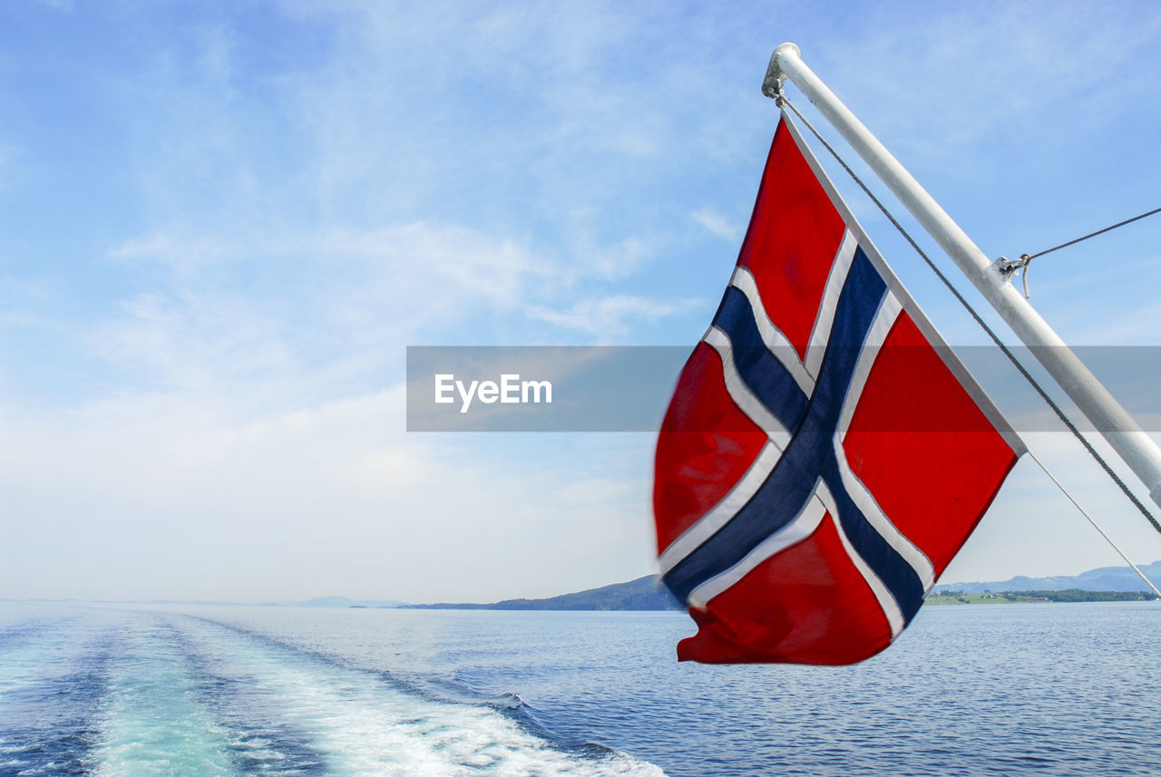 Norwegian flag over sea against sky