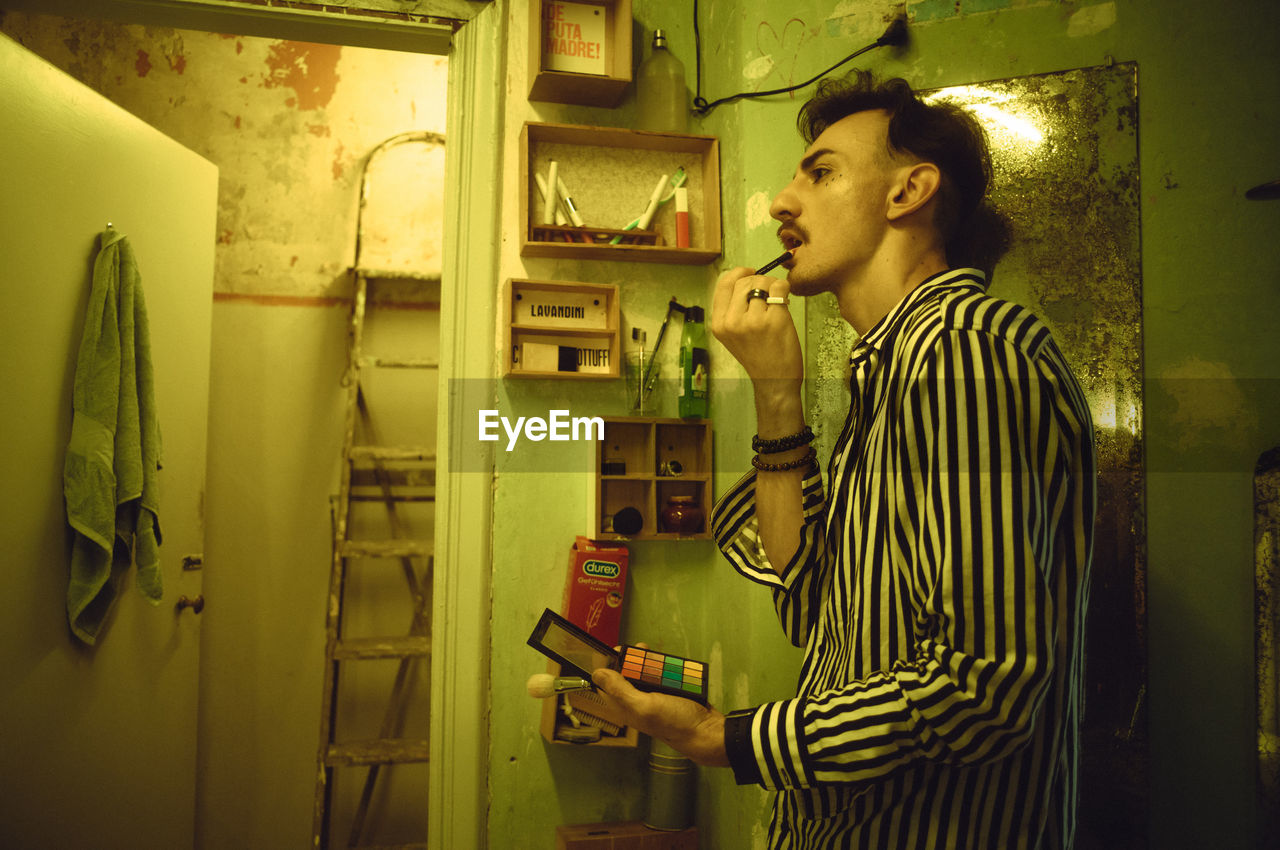 Young man applying make-up